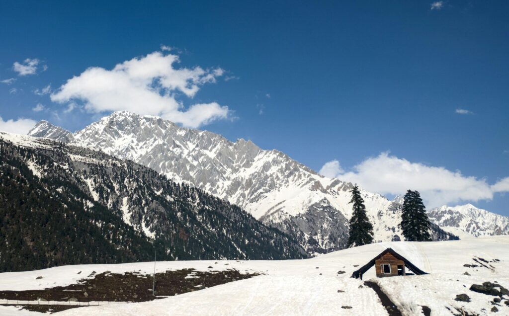 a picture of small wooden hut and snow cap mountains in the back